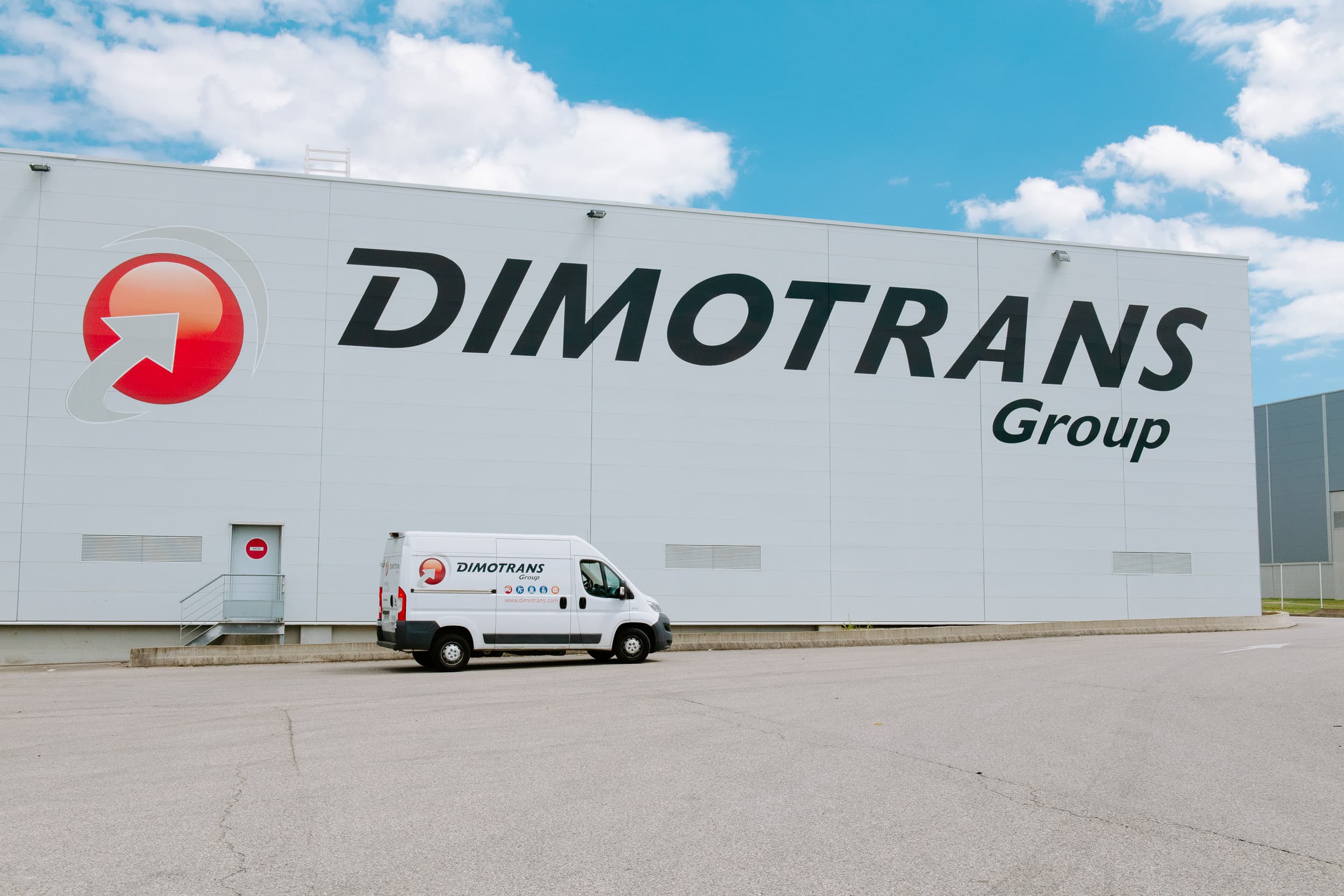 bâtiment avec logo DIMOTRANS Group avec une camionnette devant