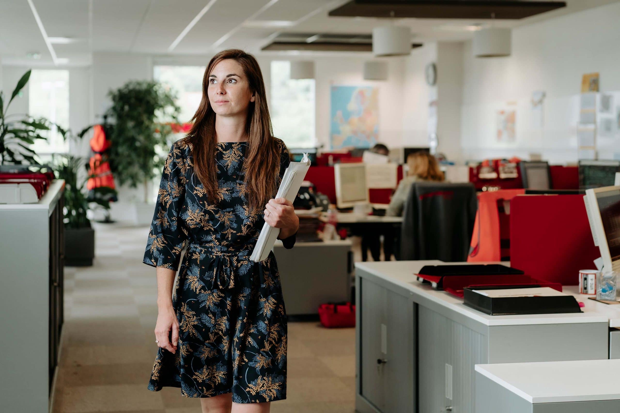 femme marchant dans un bureau avec des dossiers à la main